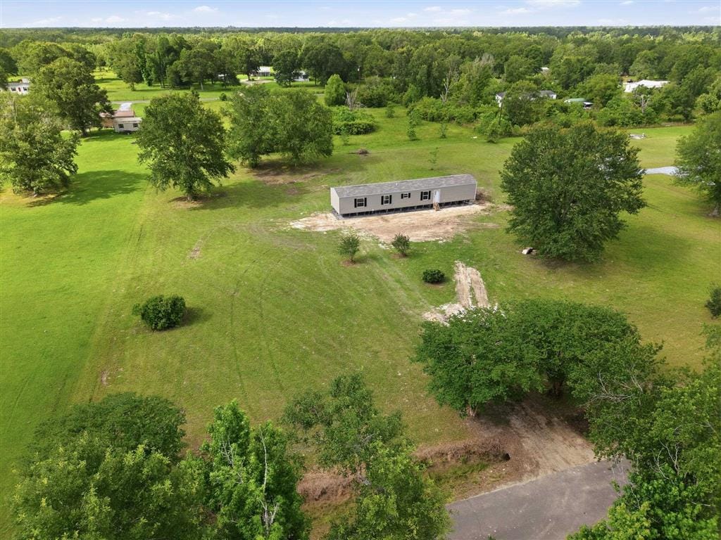 Aerial view of the new home surrounded by green acreage and trees