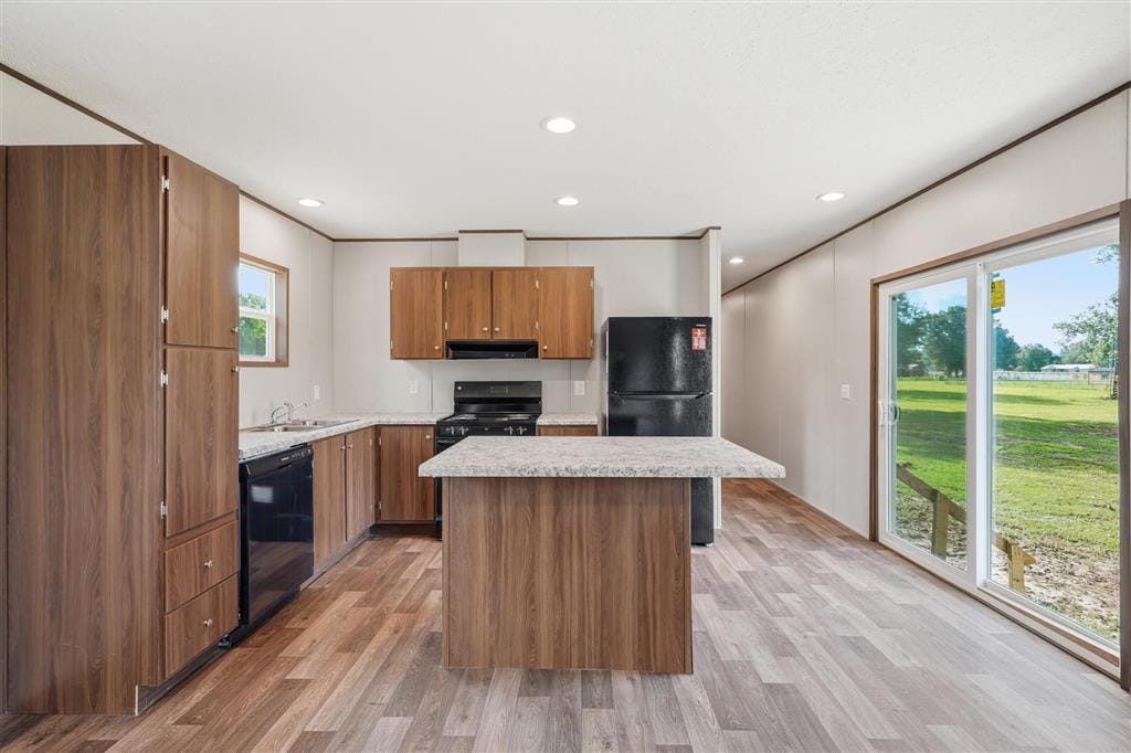 Kitchen with center island, wood cabinetry, black appliances, and sliding glass door