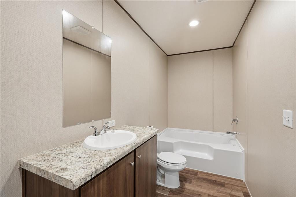 Bathroom with garden tub, vanity with stone-look counter, and toilet